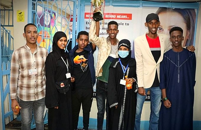 Atlas College students celebrating sports tournament championship with trophy